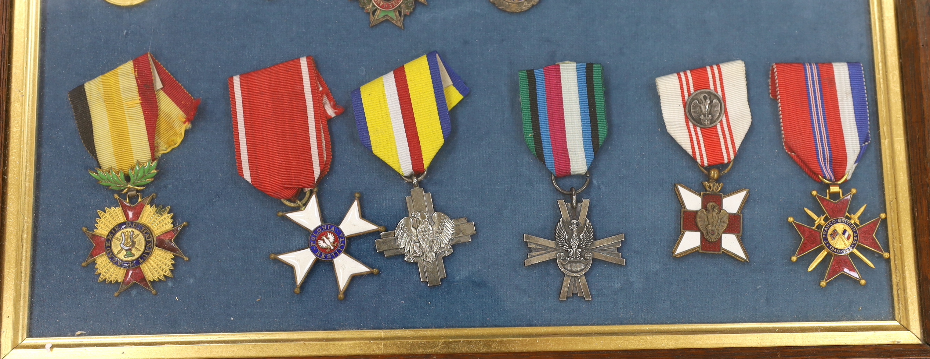 Twenty-seven medals and awards mounted in oak frames, including; French 1939-45 War Medal, Poland Lenino Cross 1943, Romanian Commemorative Medal, Belgium Red Cross Medal, etc. together with cloth shoulder titles for the